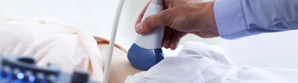 Mão segurando transdutor durante realização de exame de ultrassonografia